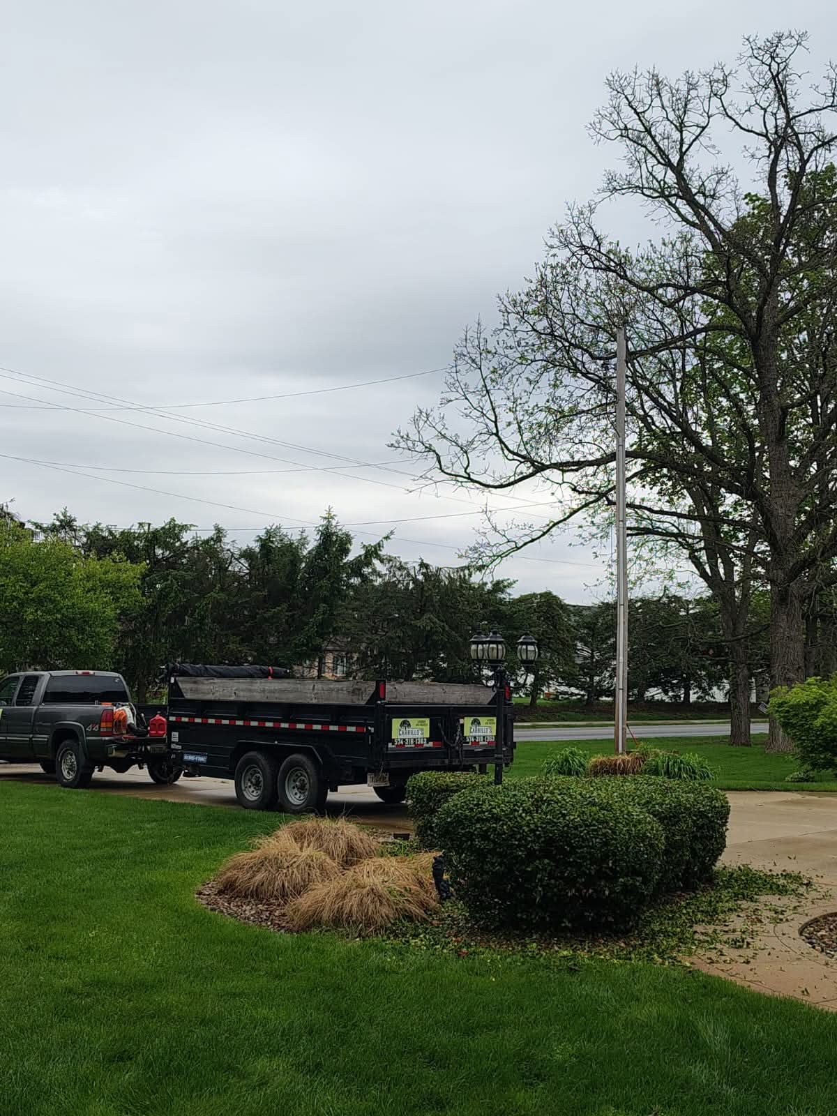 Carrillo’s pickup truck and dump trailer parked beside trimmed shrubs